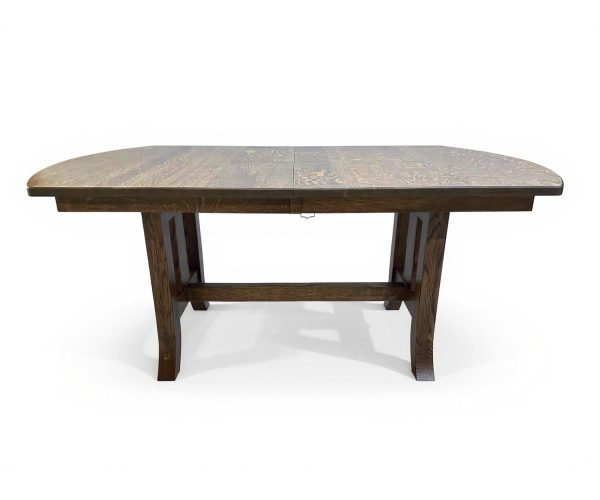 Dark wooden dining table with a centered seam indicating an extendable leaf, supported by sturdy carved legs.